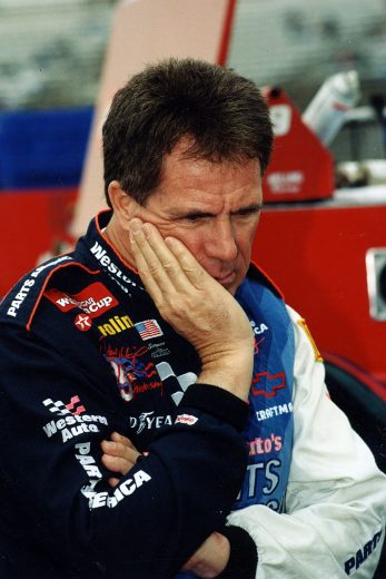 Darrell Waltrip looks on.