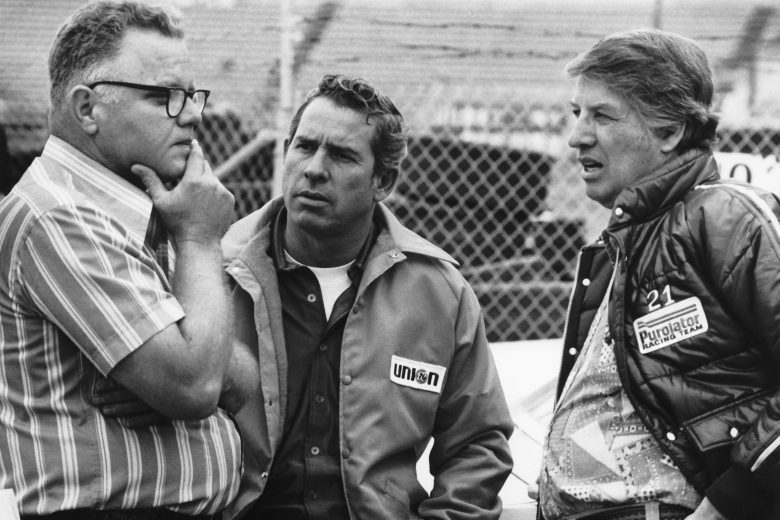 David Pearsons stands and has a conversation with two crew members.