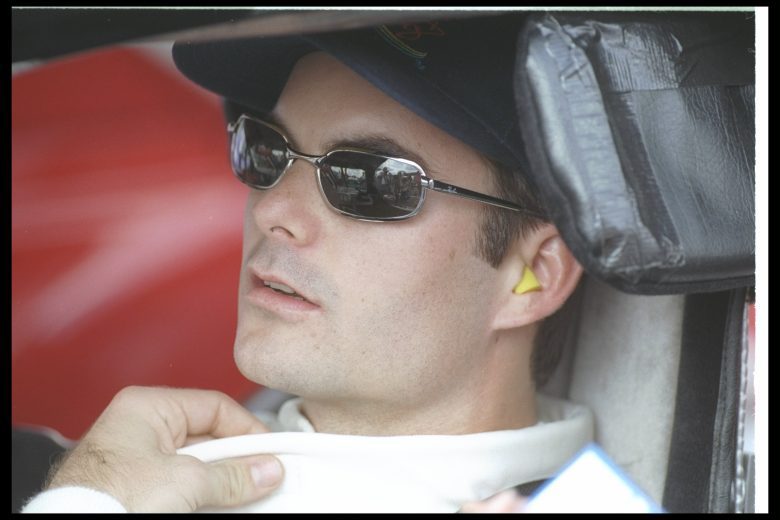 Jeff Gordon looks on in sunglasses from driver seat.
