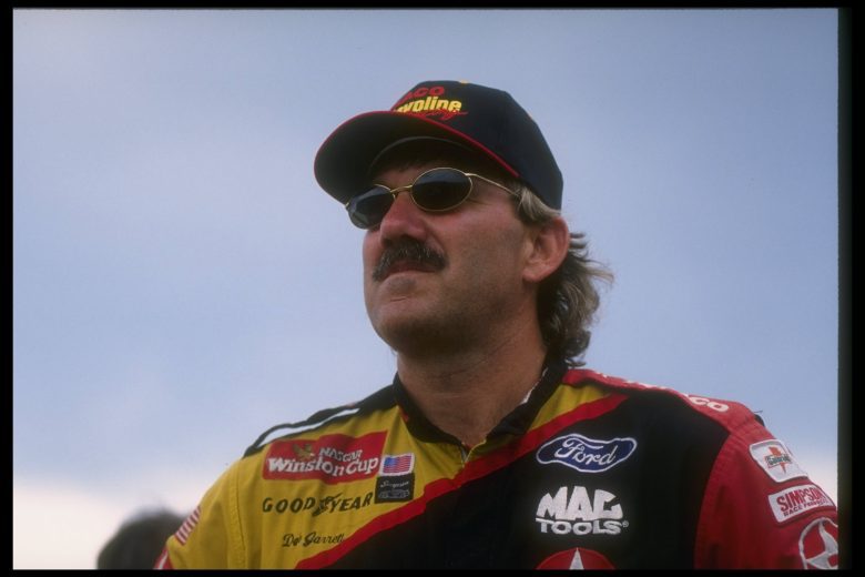 Dale Jarrett looks on in sunglasses and firesuit.