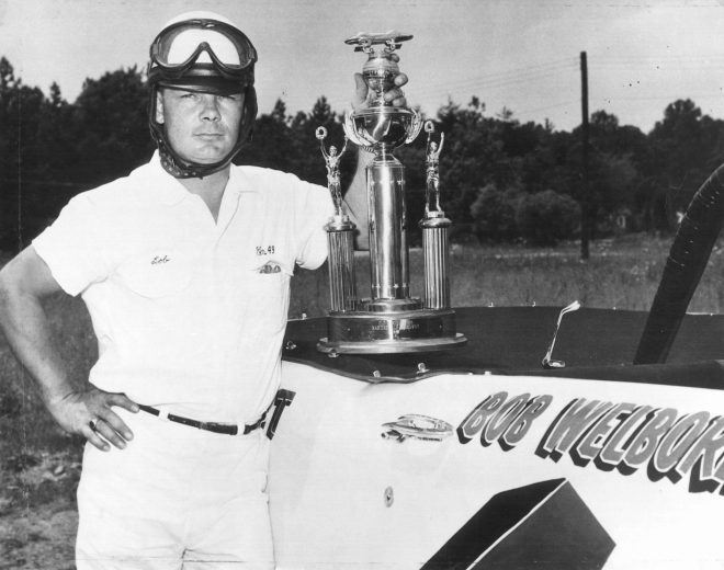 Bob Welbron poses with trophy ontop of No. 4 car.