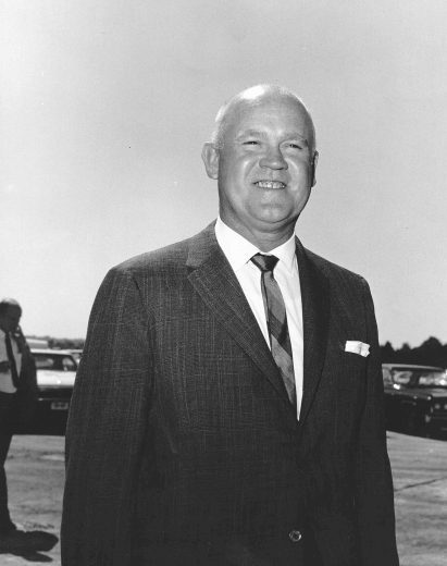H. Clay Earles smiles and looks on in suit and tie.