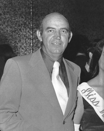 Ralph Seagraves looks on in suit and tie.