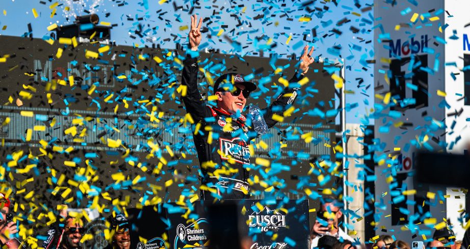 Christopher Bell celebrates in Victory Lane at Phoenix Raceway as confetti falls around him.