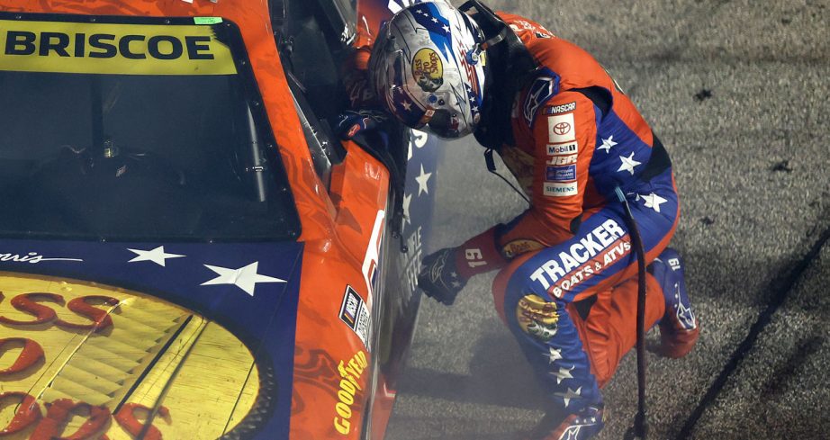 Chase Briscoe kneels next to his No. 19 Joe Gibbs Racing Toyota following his NASCAR Cup Series win at Darlington Raceway.