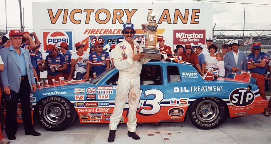 Richard Petty poses for a photo in front of his No. 43 Pontiac following his NASCAR Cup Series win at Daytona International Speedway.