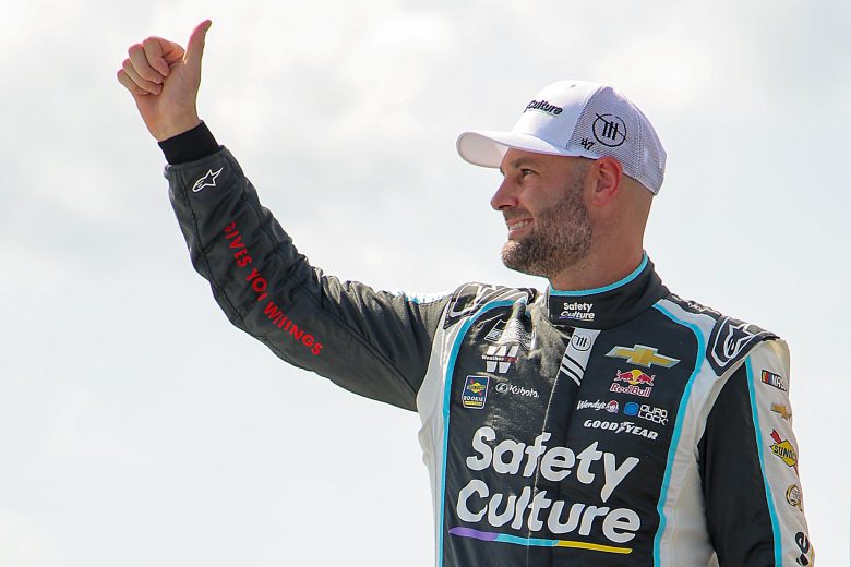 Shane van Gisbergen gives thumbs up to fans while onstage.