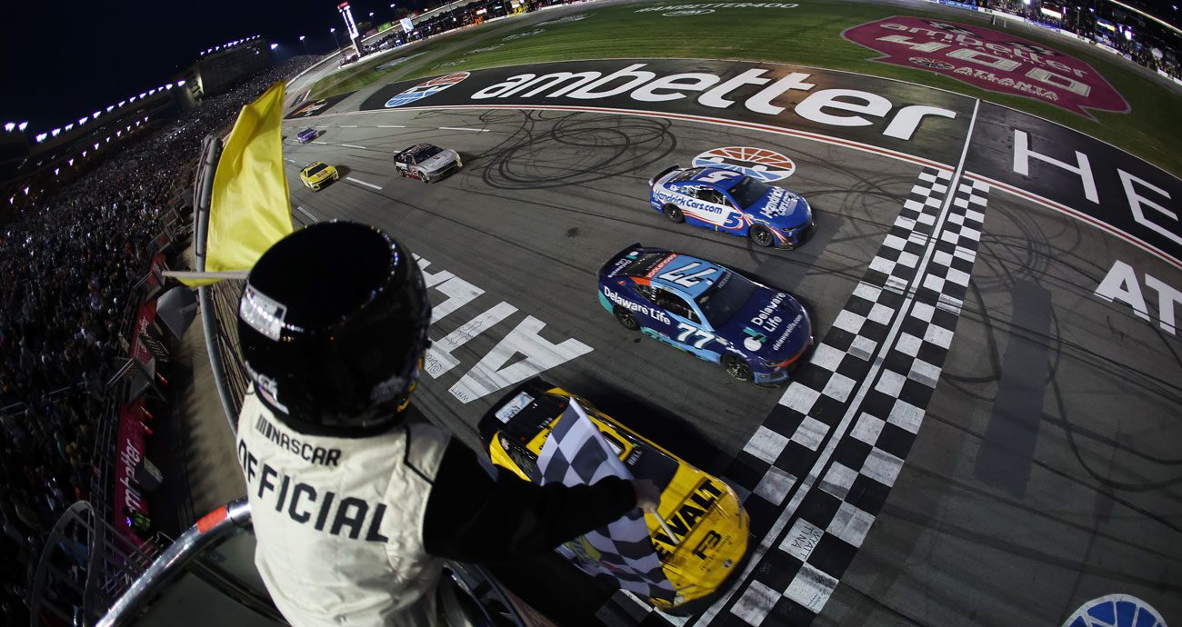 A NASCAR official waves the yellow flag and checkered flag during a NASCAR Cup Series race at EchoPark Speedway (formerly Atlanta Motor Speedway).