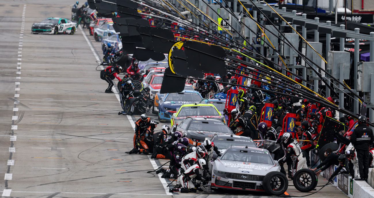 NASCAR Cup Series cars are tended to on pit road during a race at EchoPark Speedway (formerly Atlanta Motor Speedway).