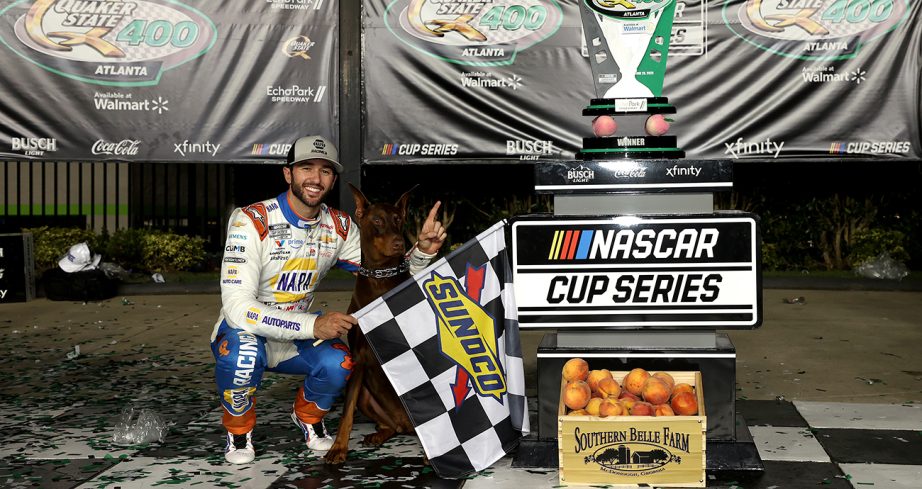Chase Elliott hold checkered flag in Victory Lane.