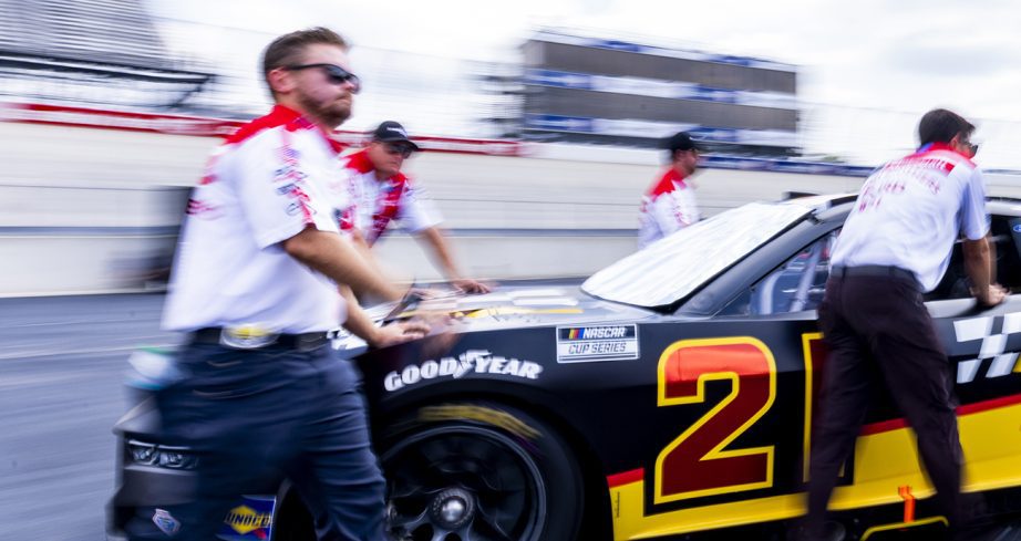 Wood Brothers Racing crew members push the No. 21 Ford out to pit road before the start of the Cup Series race at Dover Motor Speedway.