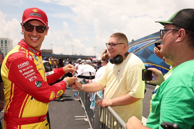 Joey Logano smiles while signing autographs.