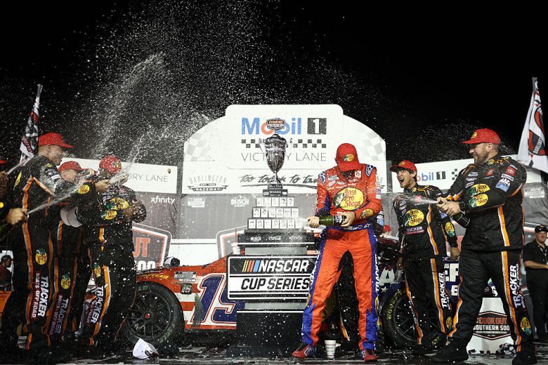 Chase Briscoe and his No. 19 Joe Gibbs Racing pit crew spray champagne in Victory Lane at Darlington Raceway.