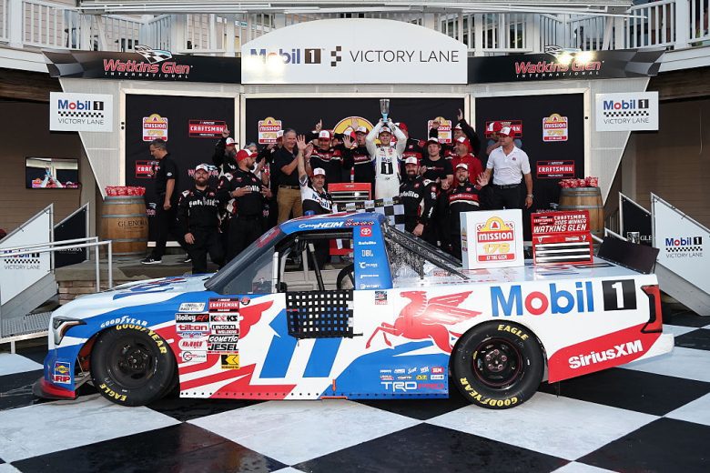 With the No. 11 Tricon Garage Toyota sitting in the foreground, Corey Heim and crew members pose for a photo in Victory Lane following their NASCAR Craftsman Truck Series win at Watkins Glen International.