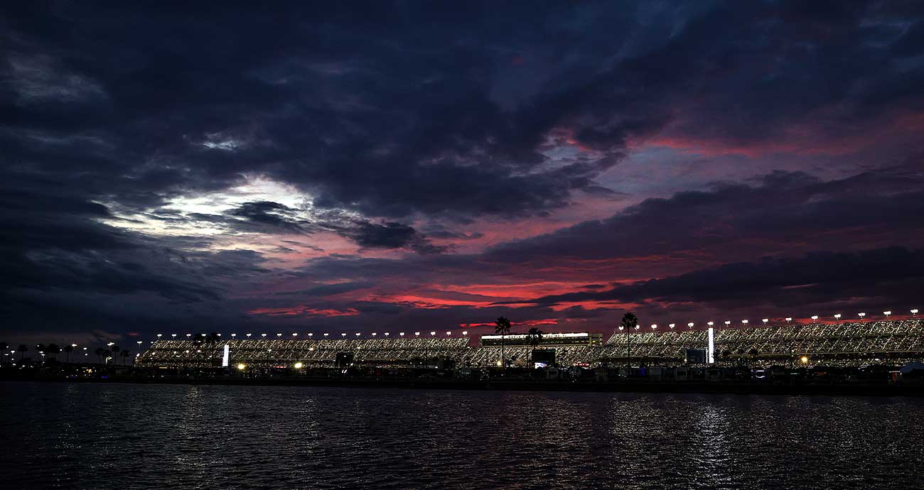 A brilliant sunset nestles behind the Daytona International Speedway grandstands and Lake Lloyd