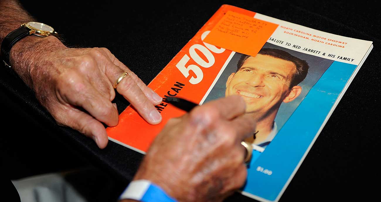 Ned Jarrett signs an autograph on a Rockingham race program during the Darlington Historic Racing Festival in 2010