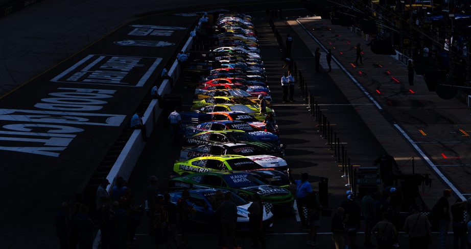 NASCAR Cup Series cars line on pit road at Bristol Motor Speedway.