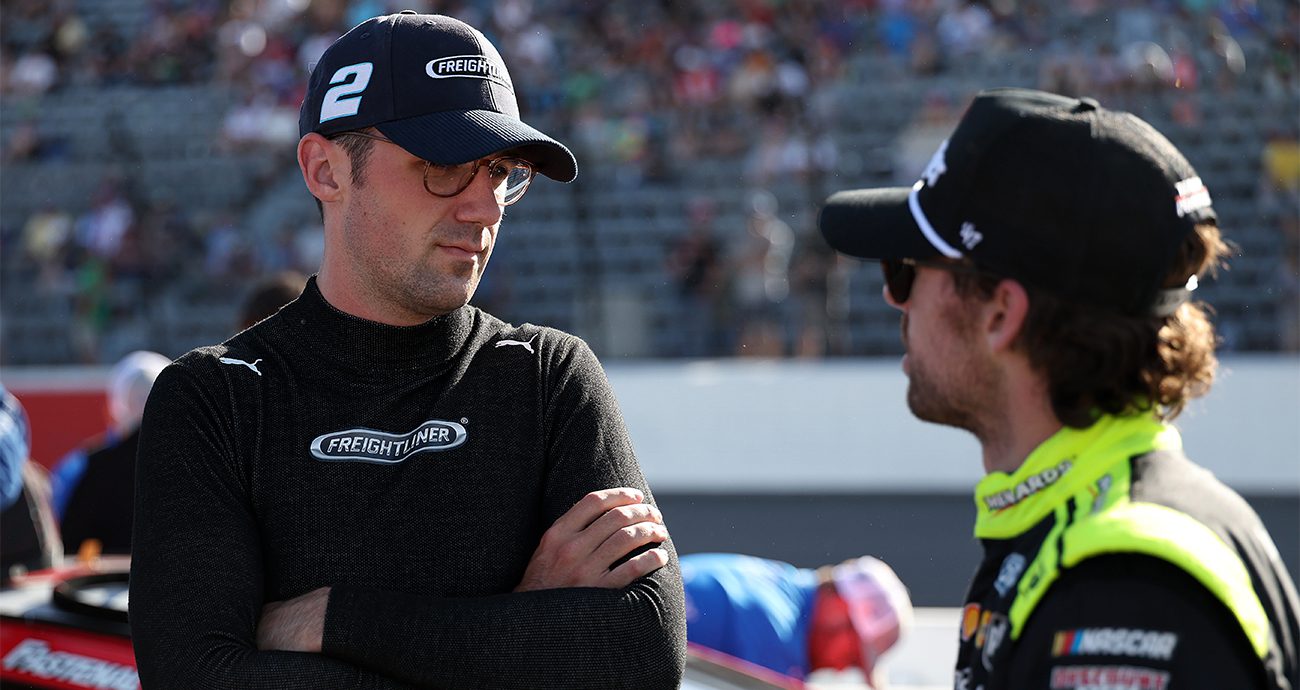 news-1300-690 NORTH WILKESBORO, NORTH CAROLINA - MAY 17: Austin Cindric, driver of the #2 Freightliner Ford, (L) and Ryan Blaney, driver of the #12 Menards/Wrangler Ford, talk on the grid during the NASCAR Cup Series All-Star Race qualifying heat #2 at North Wilkesboro Speedway on May 17, 2025 in North Wilkesboro, North Carolina.