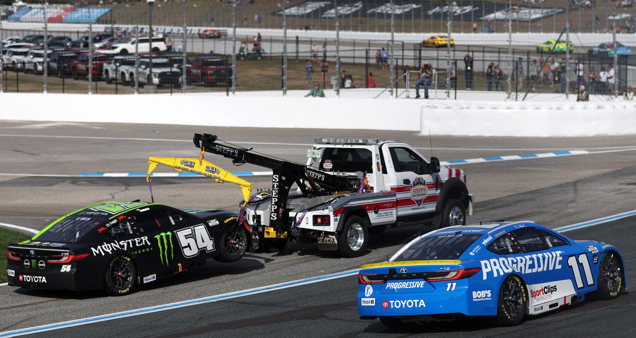 Denny Hamlin drives by the towed car of Ty Gibbs.