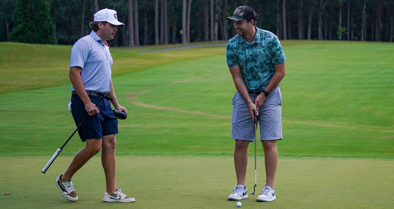 Noah Gragson talks to Chase Briscoe as he lines up a putt at Rolling Hills Country Club in Monroe, North Carolina.