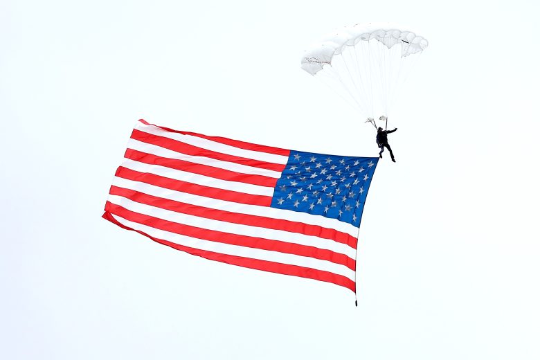 A parachuter lands with the American flag.