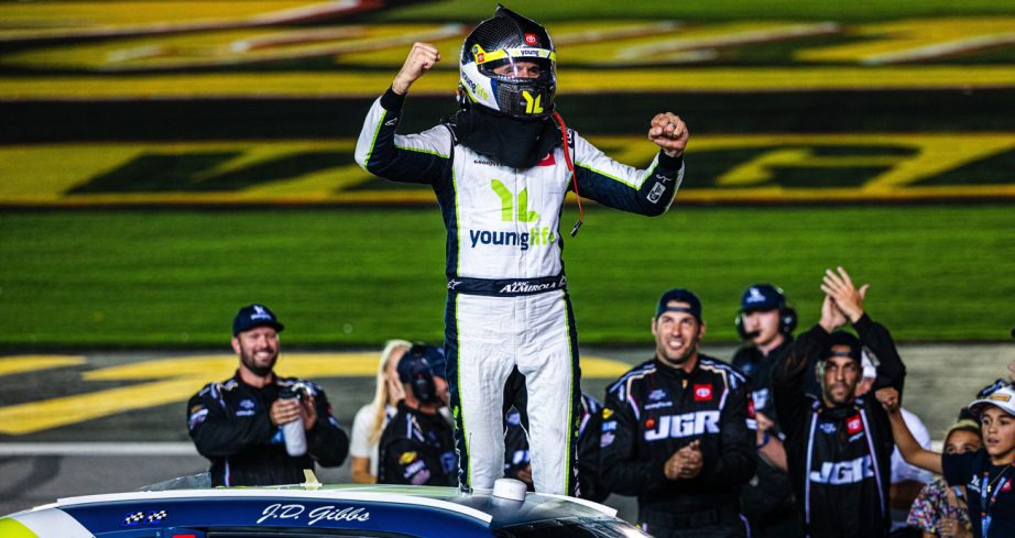 Aric Almirola cheers to the crowd at Las Vegas Motor Speedway as his pit crew stand in the background.