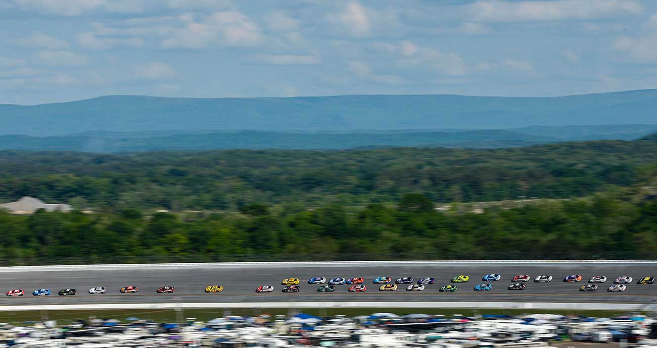 The Cup Series field roars through the high-banked turns at Talladega Superspeedway with mountains in the background