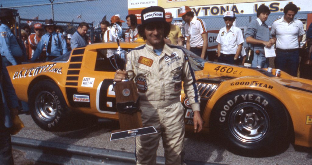 Richie Evans stands in Victory Lane with a trophy at Daytona.