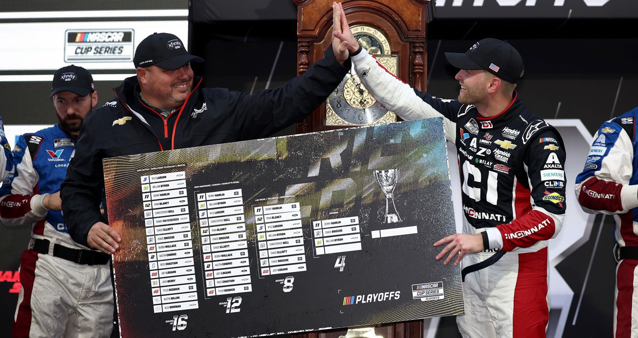 Rudy Fugle (left) claps with William Byron (R) in Victory Lane at Martinsville Speedway while holding a NASCAR Cup Series Playoffs grid.