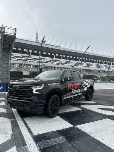 A Pocono Raceway truck sits parked at the start/finish line as snow falls.