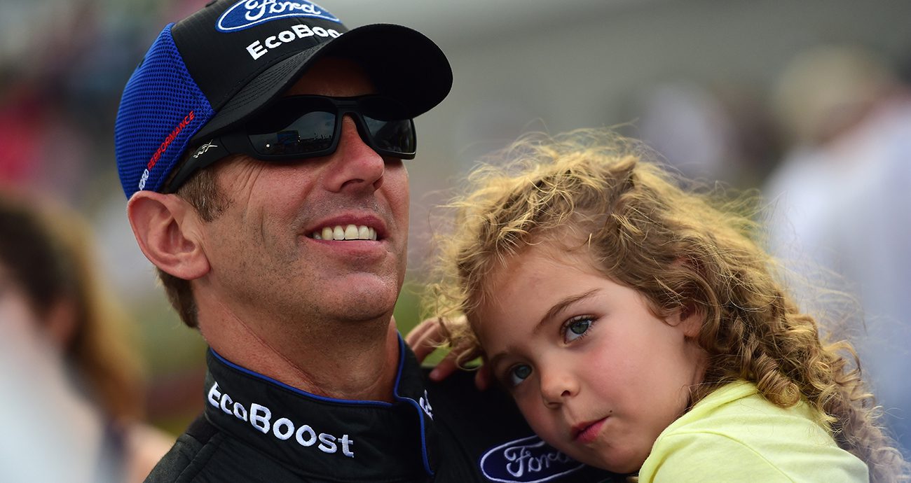 greg biffle smiles while holding his daughter