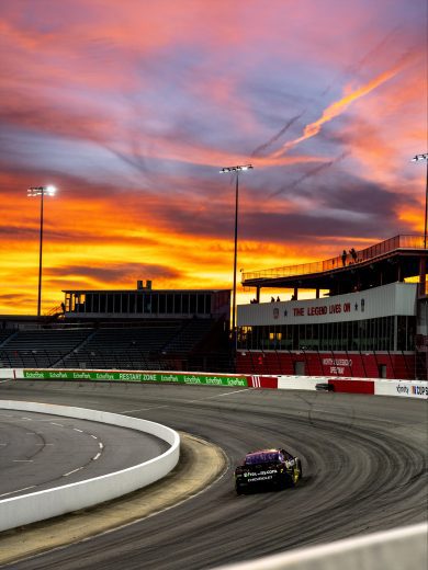 Daniel Suárez drives No. 7 Chevrolet at North Wilkesboro Speedway during sunset.