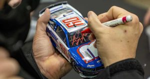 Ryan Preece signs a No. 60 RFK Racing Ford diecast car during the Clash Preview at the Winston-Salem Fairgrounds