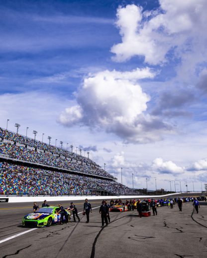 NASCAR Cup Series cars get pushed to the grid at Daytona International Speedway.