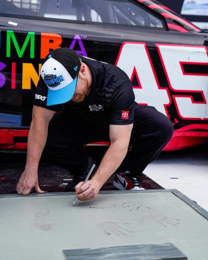 Tyler Reddick signs his hand and foot imprints.