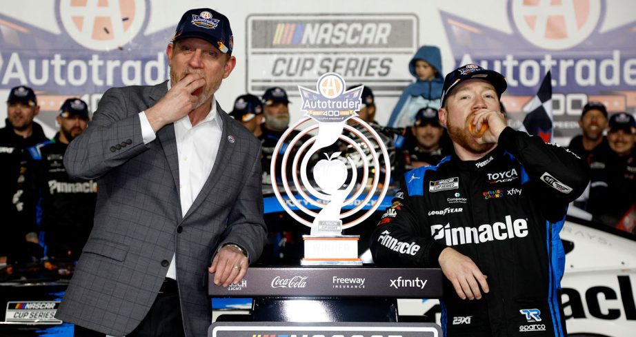 Tyler Reddick (R) eats a peach in Victory Lane.