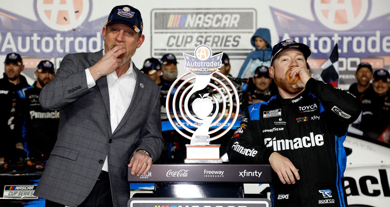 Tyler Reddick (R) eats a peach in Victory Lane.