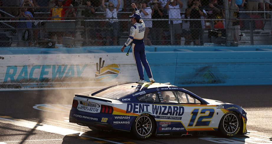 Ryan Blaney stands on top of car.