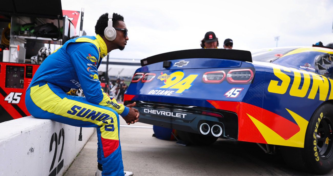 Lavar Scott sits on wall and looks at his race race car.