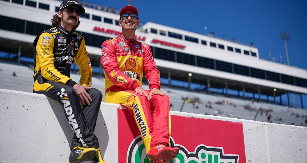 Team Penske teammates Ryan Blaney, left, and Joey Logano sit on the pit wall before Cup Series practice at Martinsville Speedway