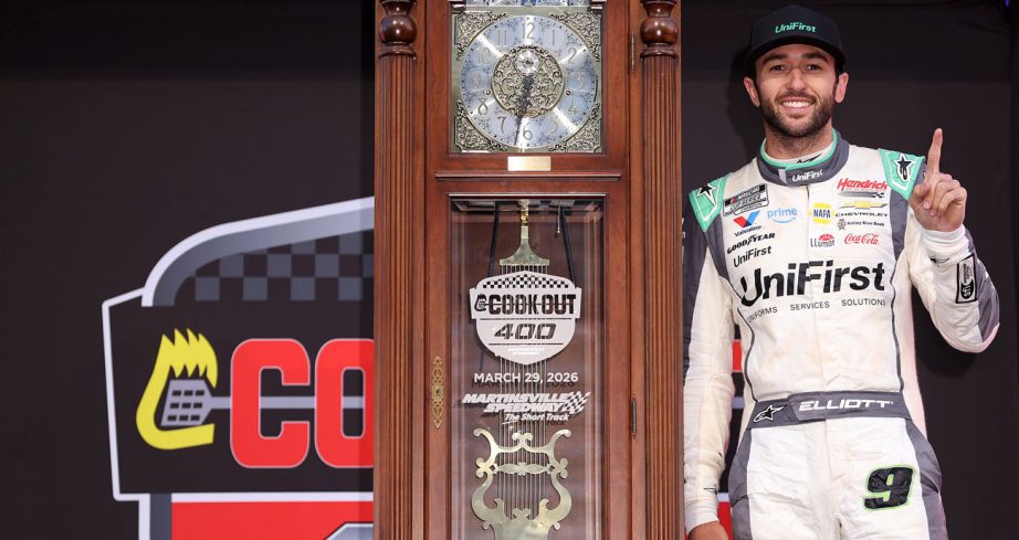 Chase Elliott poses with the grandfather clock in Victory Lane following his NASCAR Cup Series win at Martinsville Speedway.