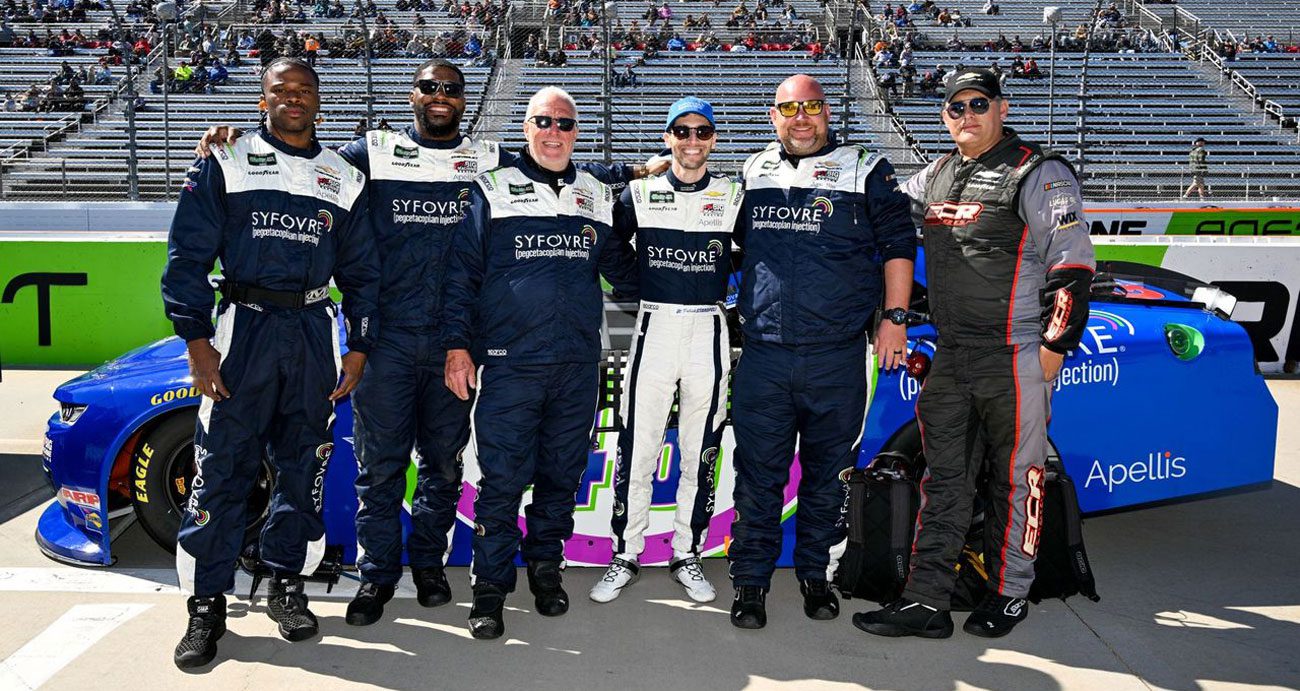 Patrick Staropoli poses for a photo with his pit crew before a NASCAR O'Reilly Auto Parts Series race.