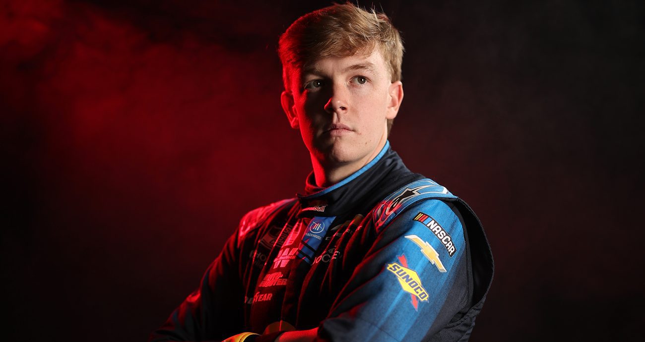 Connor Zilisch stands with arms folded across his chest as he looks up and to his left in a posed photo at NASCAR Productions Day on Jan. 20, 2026 in Charlotte, North Carolina.