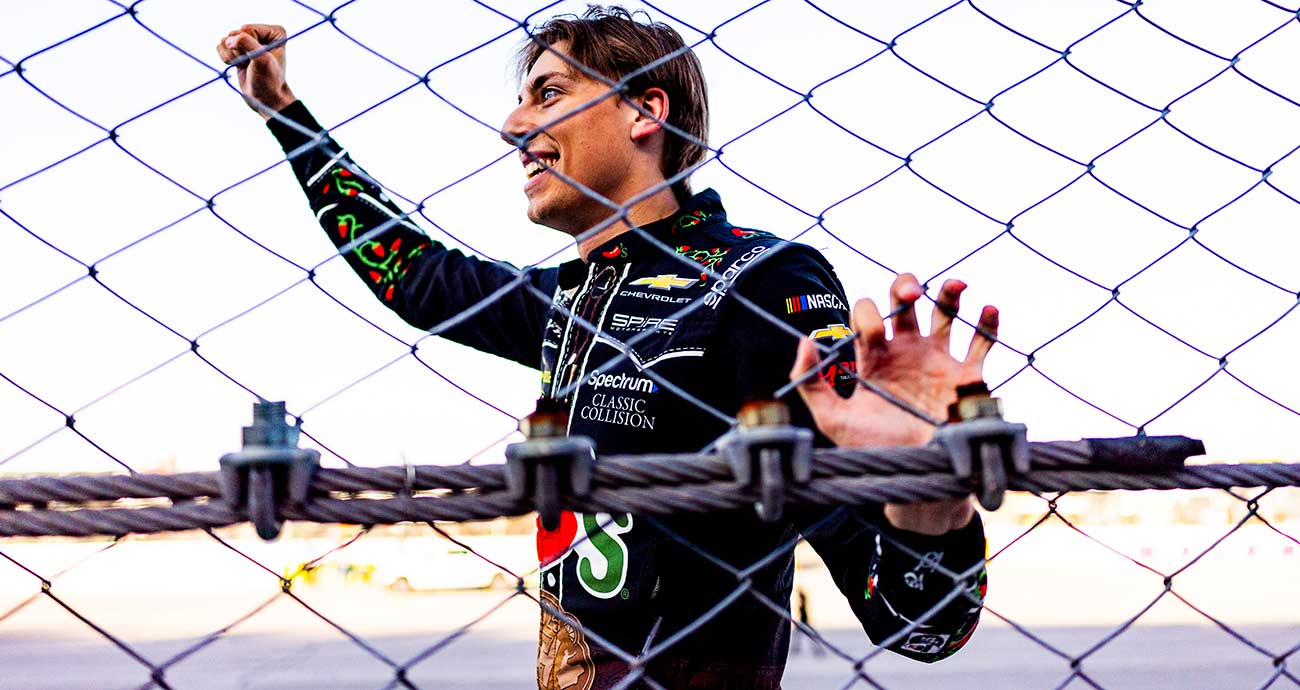 Carson Hocevar signals to fans as he celebrates at the frontstretch catchfence at Talladega Superspeedway
