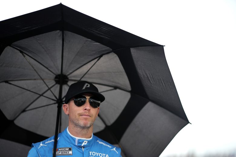 Denny Hamlin walks with an umbrella.