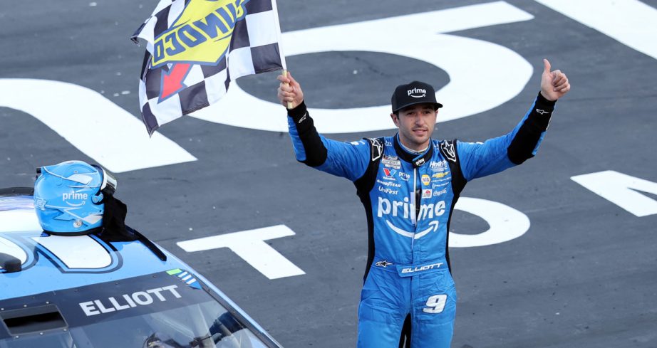 Chase Elliott raises the checkered flag to the crowd at Texas Motor Speedway.