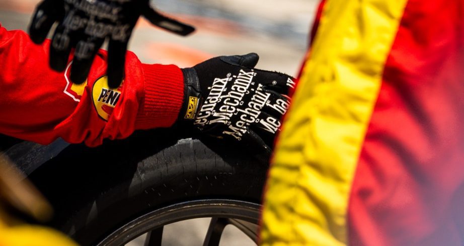 Pit crew member holds tire.