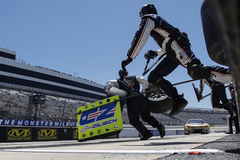 Pit crew jumps over wall.
