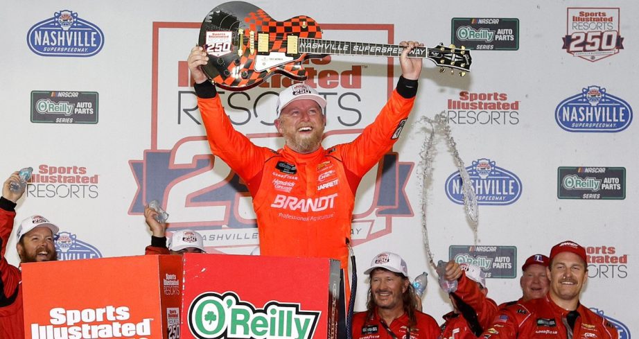 Justin Allgaier holds up the race winning guitar after winning at Nashville Superspeedway.