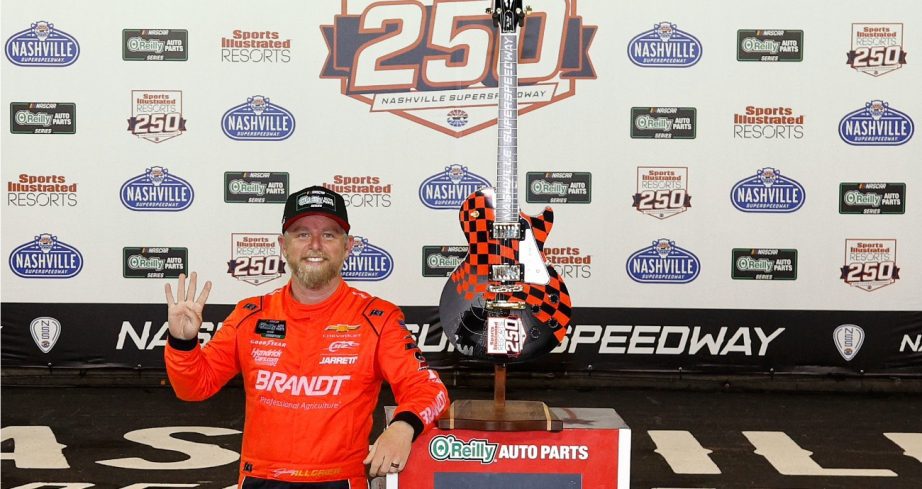 Justin Allgaier stands next to race winning trophy.